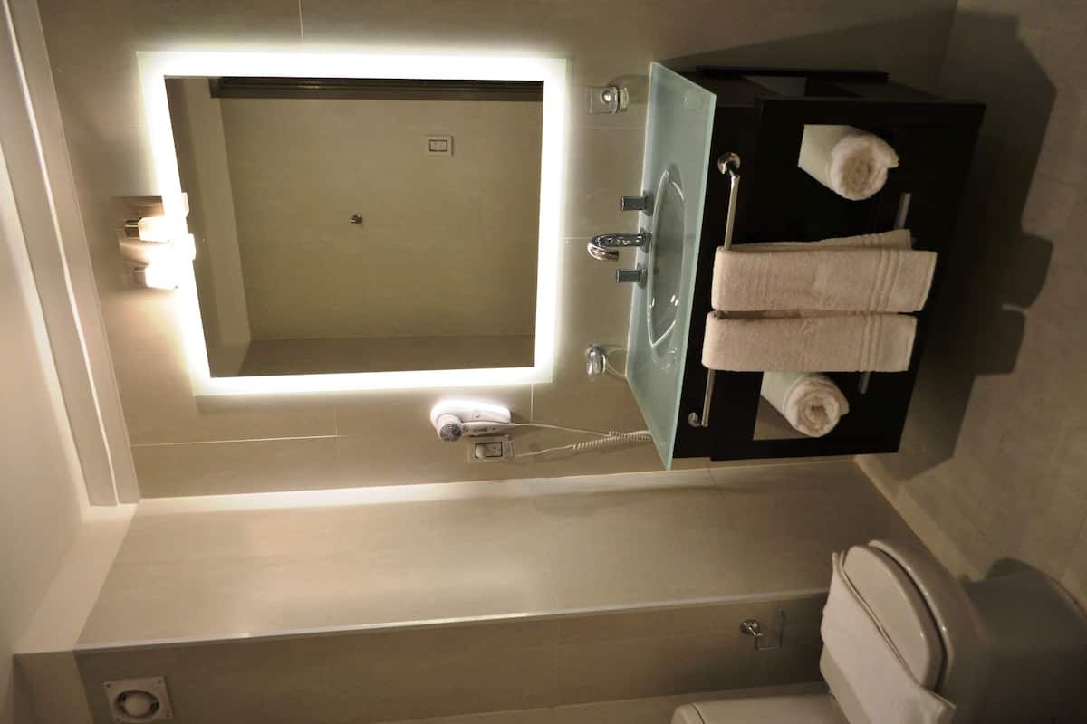 A modern bathroom with a large mirror, a built-in sink, and a toilet.