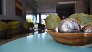 Una habitación con una mesa redonda, un cuenco de madera con adornos y un sofá estampado.