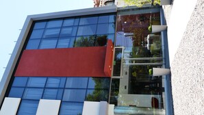 Un edificio moderno con amplios ventanales y una pared de acento roja.