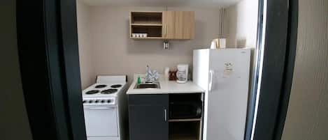 A compact kitchen with a stove, sink, and refrigerator.