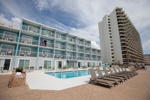 A hotel with a pool, multiple balconies, and a large building with a unique curved facade. - Garden City Inn (Murrells Inlet)