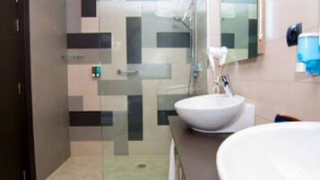 Une salle de bain moderne avec une douche à parois de verre, un lavabo blanc et un miroir.
