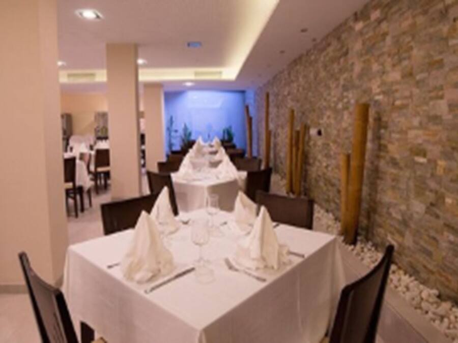 Un restaurant avec des tables dressées pour le service, un mur en pierre et une vue sur l’intérieur.