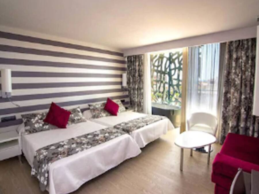Ett hotellrum med två sängar, ett litet bord, en stol och utsikt över omgivningarna.
