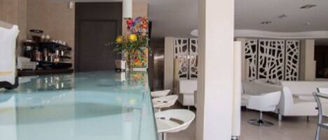 Una cocina moderna con encimera de vidrio, armarios blancos y un florero decorativo con flores.
