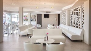 Un moderno vestíbulo de hotel con sofás blancos, una mesa redonda y una pared decorativa.
