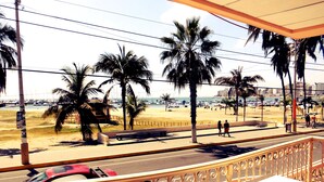 A balcony with a view of a beach, palm trees, and parked cars. - Hotel Francisco II (Salinas)