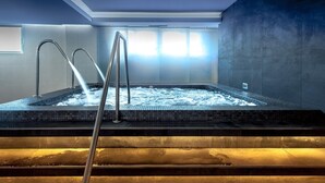 A hot tub with a metal ladder, surrounded by tiled walls and a window with natural light.