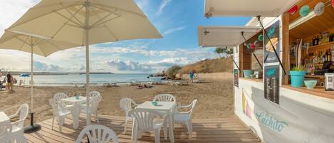 A beachside café with outdoor seating and a view of the sea.