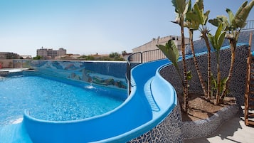 Una piscina al aire libre, sombrillas, sillones reclinables de piscina