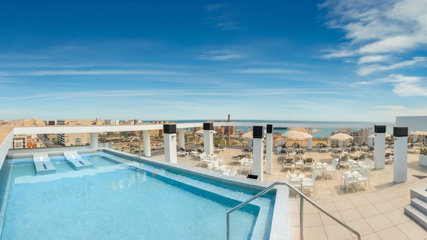 A rooftop pool with a view of the ocean and cityscape.
