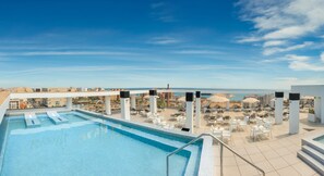 Una piscina al aire libre, sombrillas, tumbonas