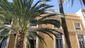 A building with a yellow facade, multiple balconies, and a palm tree in the foreground. - Apartamentos Santa Faz by Be Alicante (Alicante)
