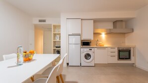 A compact kitchen with a washing machine, microwave, and oven. - Apartamentos Santa Faz by Be Alicante (Alicante)