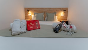 A hotel room with a wooden headboard, two bedside lamps, a bed with white linens, a red gift box, and two towels. - Apartamentos Santa Faz by Be Alicante (Alicante)