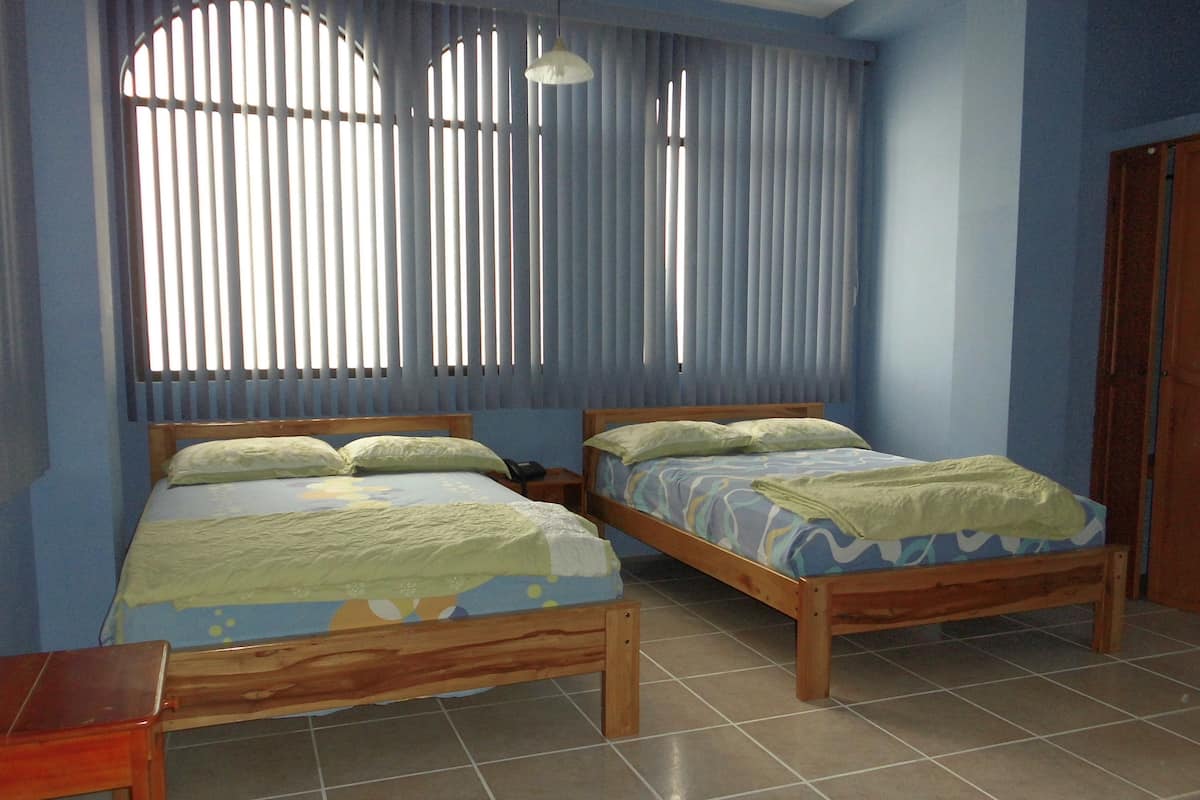 Un dormitorio con dos camas de madera, una mesita de noche, un escritorio y un armario.