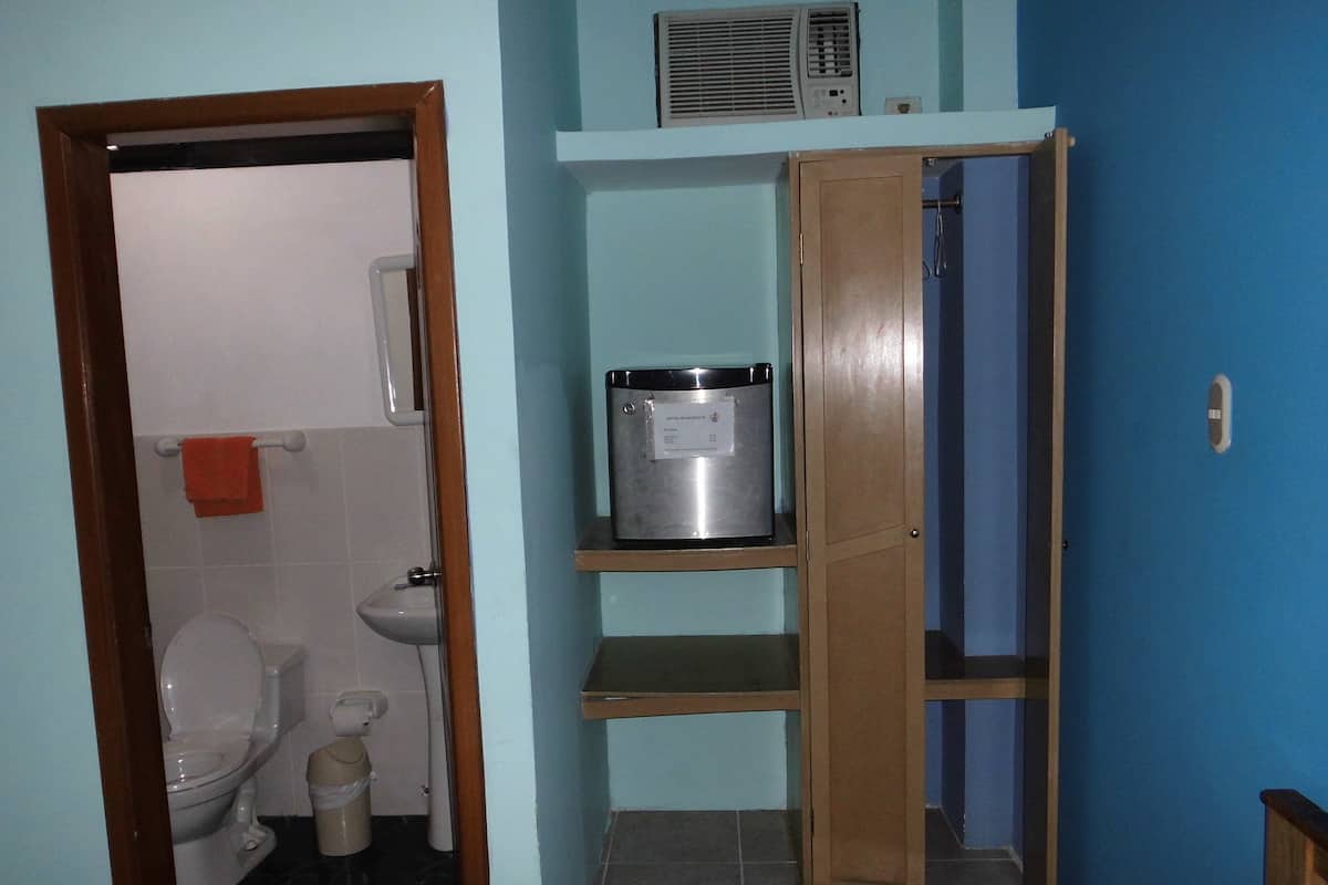 Un baño con inodoro, lavamanos y repisa con calentador de agua.