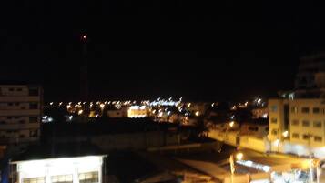 Vista nocturna de un paisaje urbano con edificios iluminados y una torre destacada.