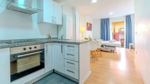 A modern kitchen with a built-in oven and a dining area with a table and chairs. - Apartamentos Globus by Be Alicante (Alicante)