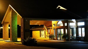 Fachada de hotel de ladrillo, con amplias ventanas y zona de estar al aire libre.