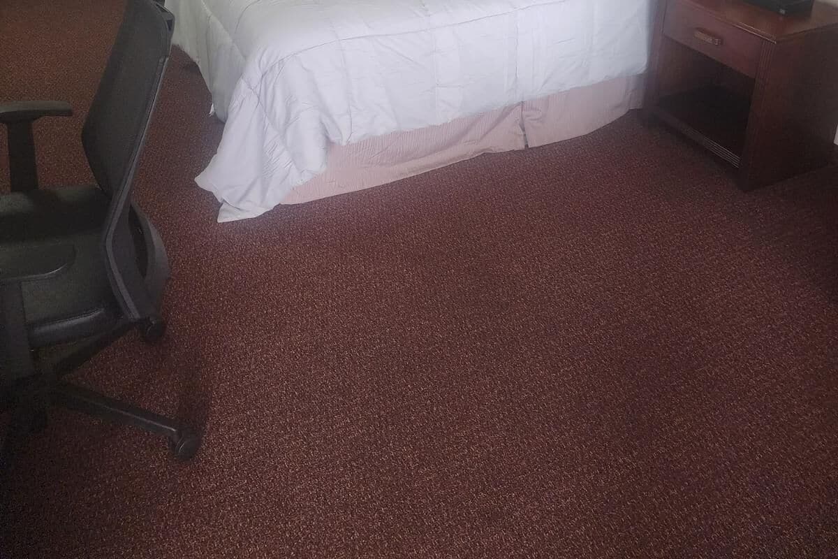 Une chambre d’hôtel avec deux lits simples, un bureau, une chaise et une lampe.