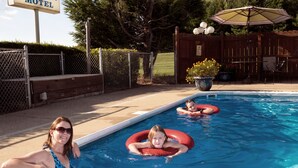 Una piscina con un letrero del motel Four Seasons al fondo.