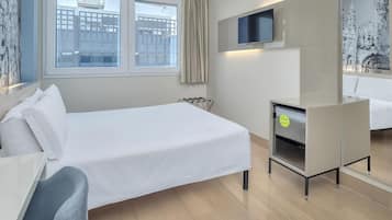 Una camera d'albergo con un letto, una scrivania, una sedia, un televisore e uno specchio da bagno.