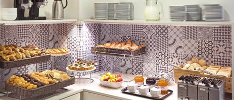 A buffet with various food items, including fruits, pastries, and condiments.