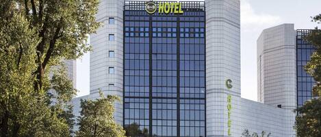 A modern hotel building with a prominent 'HOTEL' sign on the facade, featuring a grid-like window pattern.