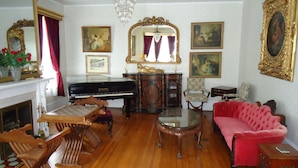 Un salón formal con un piano de cola, un sofá rojo y una araña.