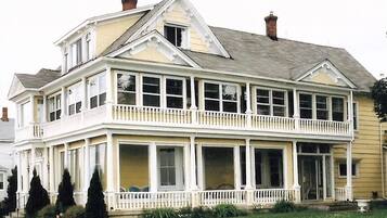 A two-story house with a balcony, large windows, and a chimney.