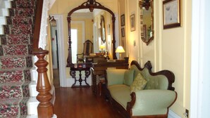 Una gran escalera con alfombra floral, una silla de madera y una lámpara.