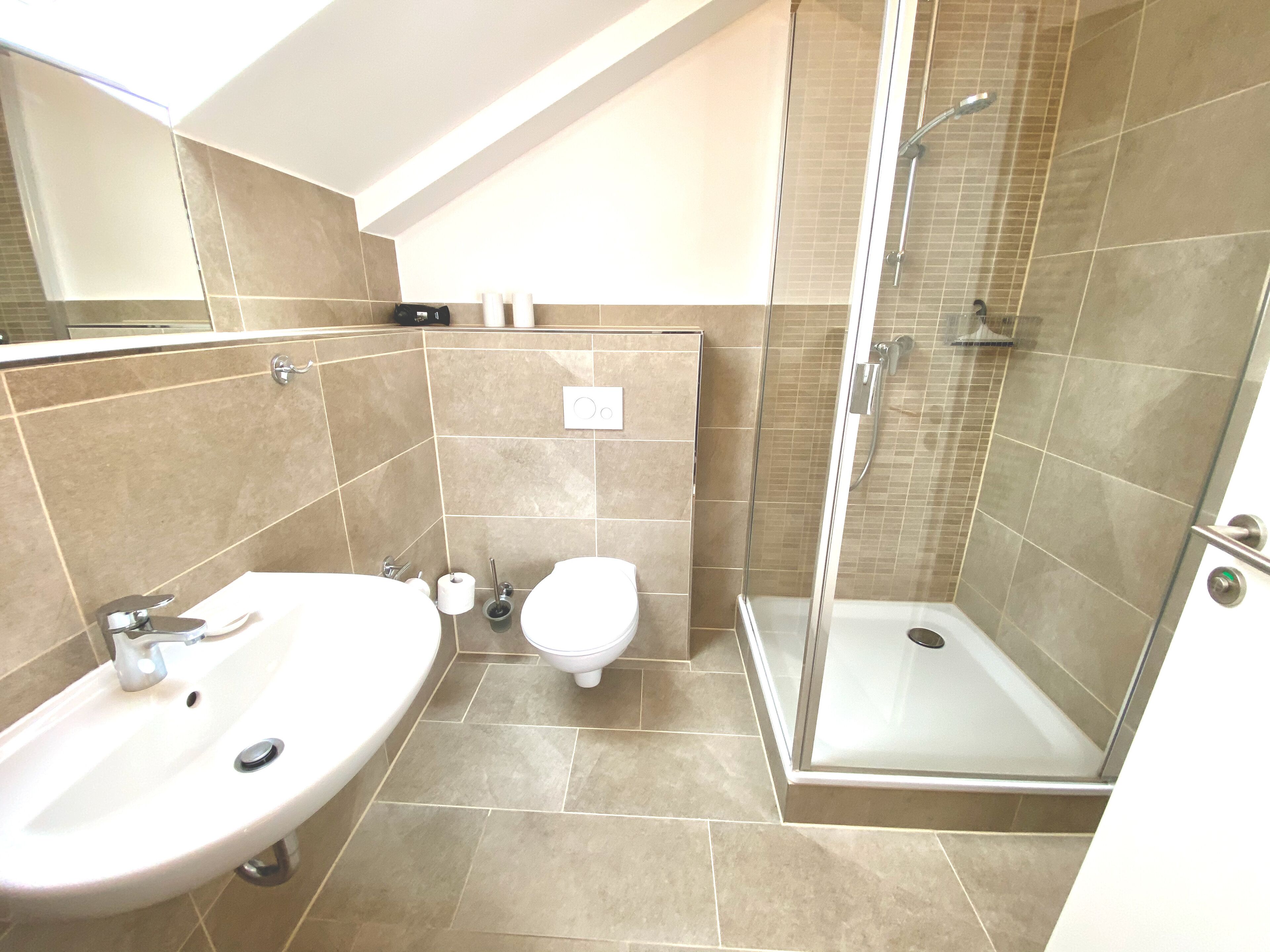A modern bathroom with a shower, two sinks, and a toilet.