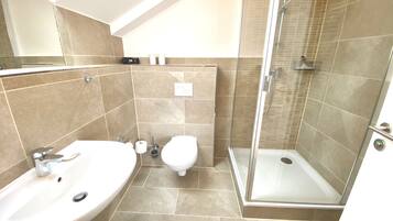 A modern bathroom with a shower, two sinks, and a toilet.