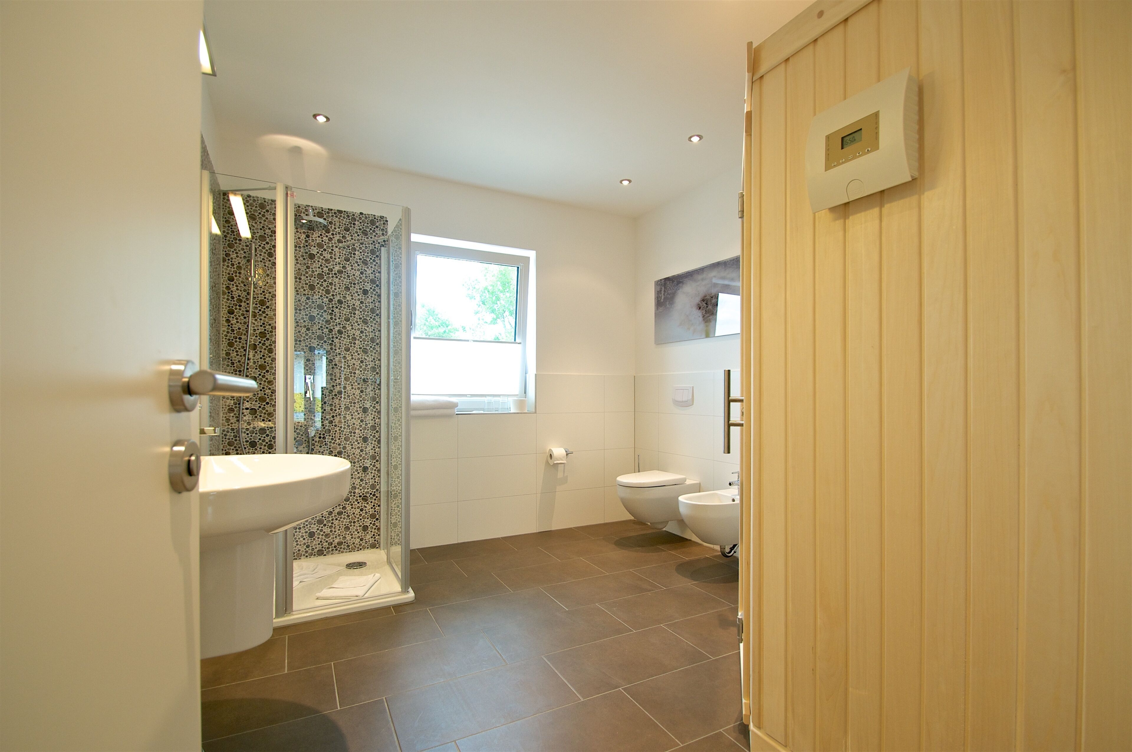 A modern bathroom with a shower, toilet, and sink.