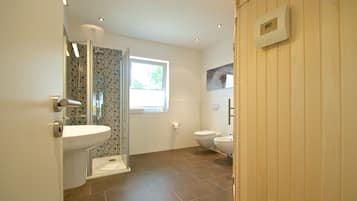 A modern bathroom with a shower, toilet, and sink.