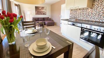 A modern kitchen with white cabinets, a tiled backsplash, and a built-in oven.
