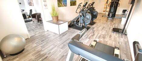 A gym with exercise equipment, a treadmill, and a small table with a plant.