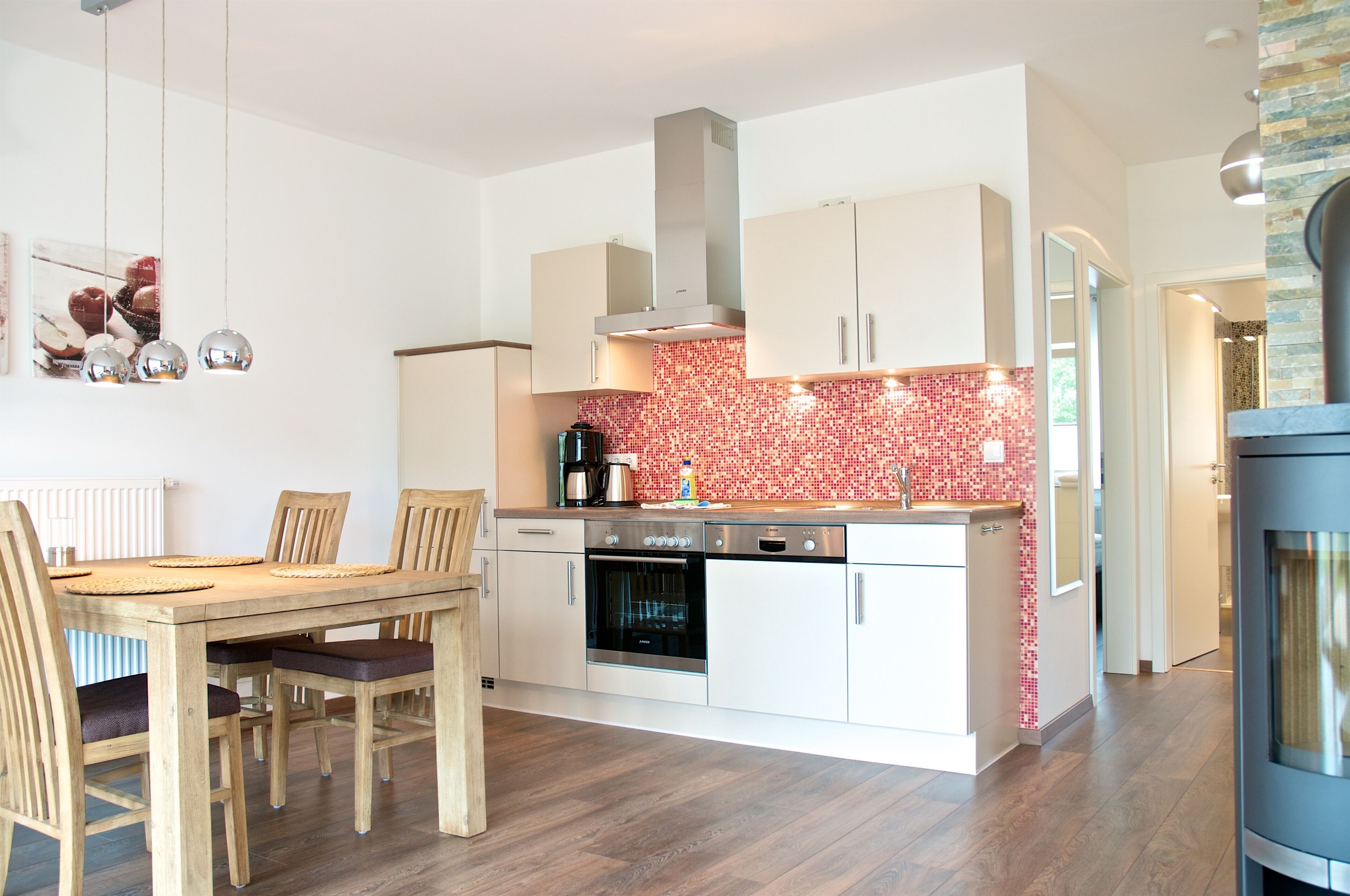 A modern kitchen with white cabinets, a red-tiled backsplash, and a built-in oven.