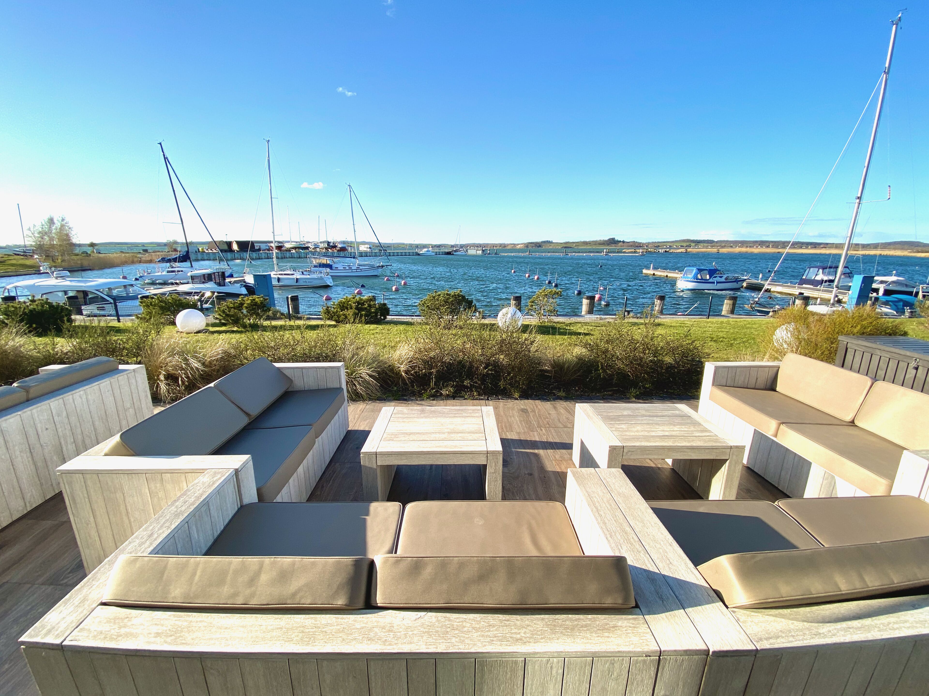 Un espace extérieur aménagé avec des sièges et offrant une vue sur un port de plaisance.