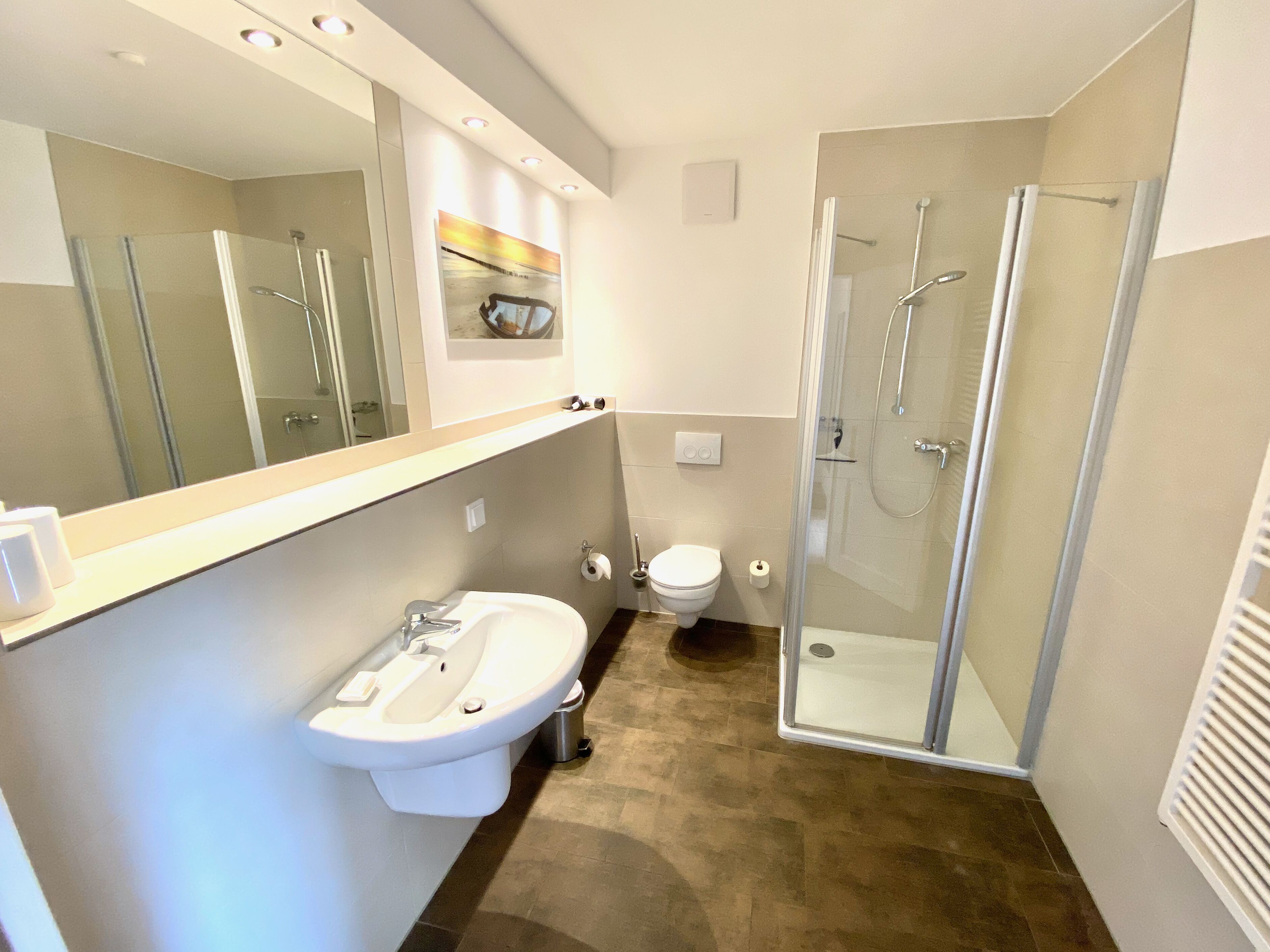 A modern bathroom with a glass-enclosed shower, a white sink, and a toilet.