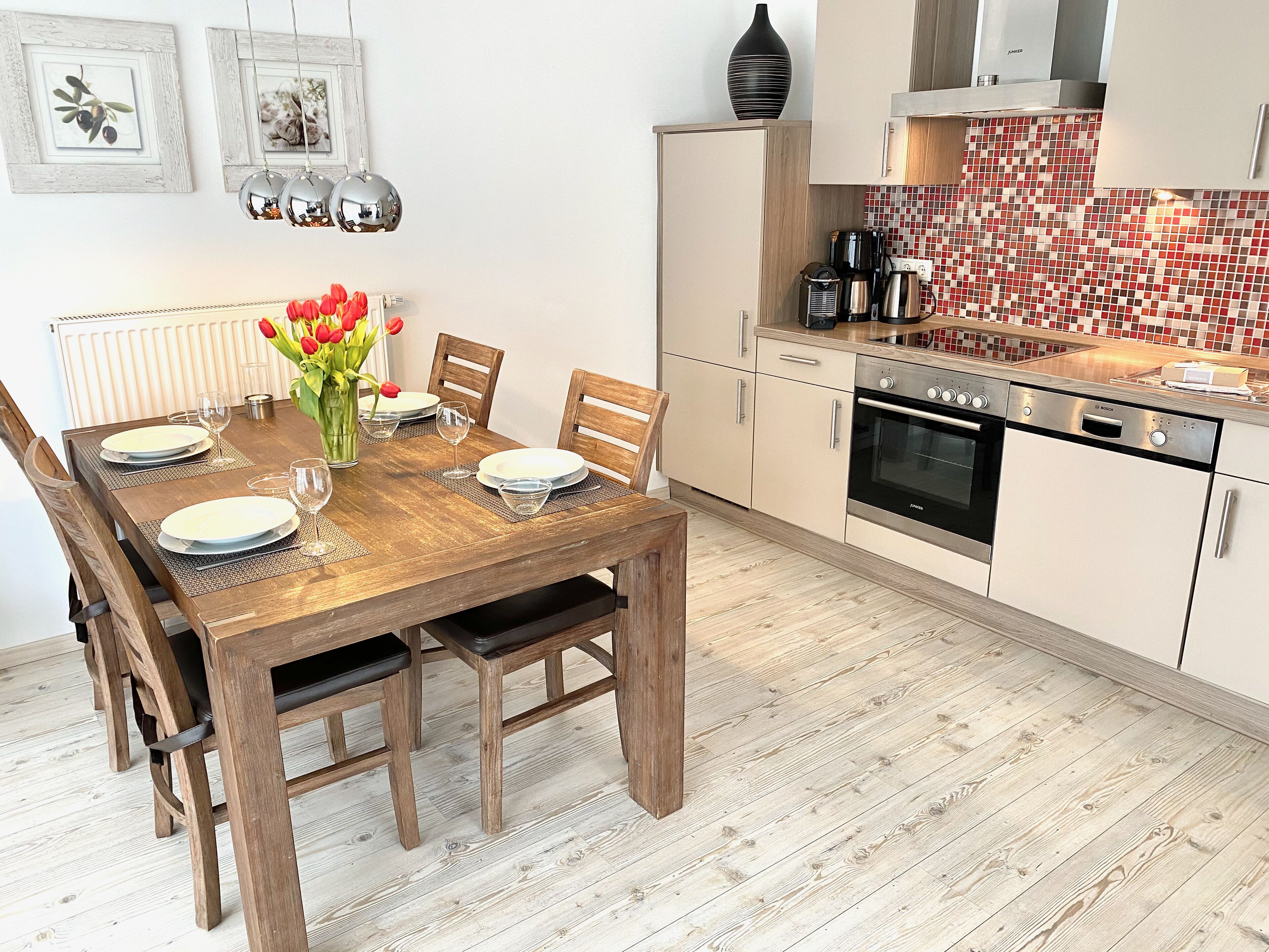 A modern kitchen with white cabinets, a Bosch oven, and a tiled backsplash.
