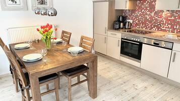 A modern kitchen with white cabinets, a Bosch oven, and a tiled backsplash.