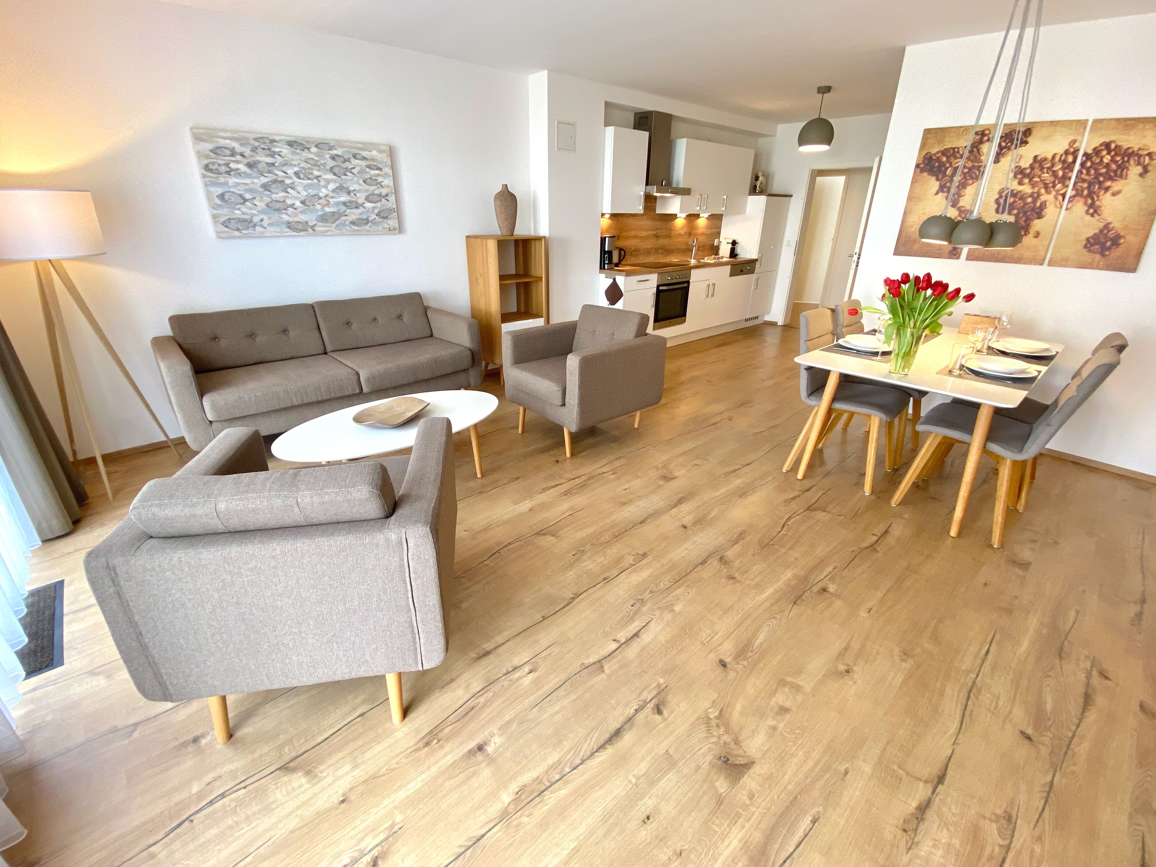 A modern living room with a sofa, two armchairs, a coffee table, and a dining area with a table and chairs.