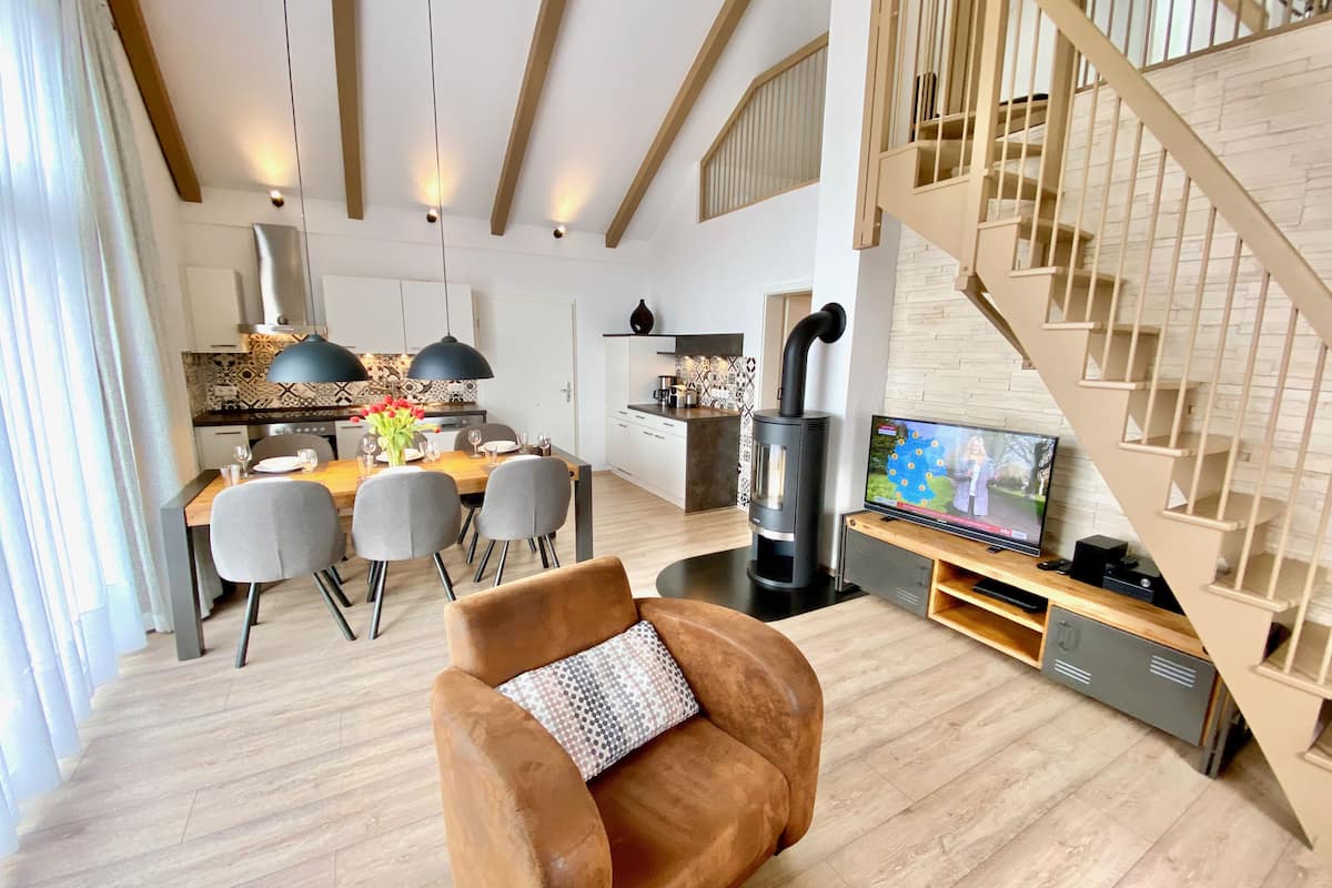 A modern living room with a wooden floor, a sofa, a TV, and a fireplace.