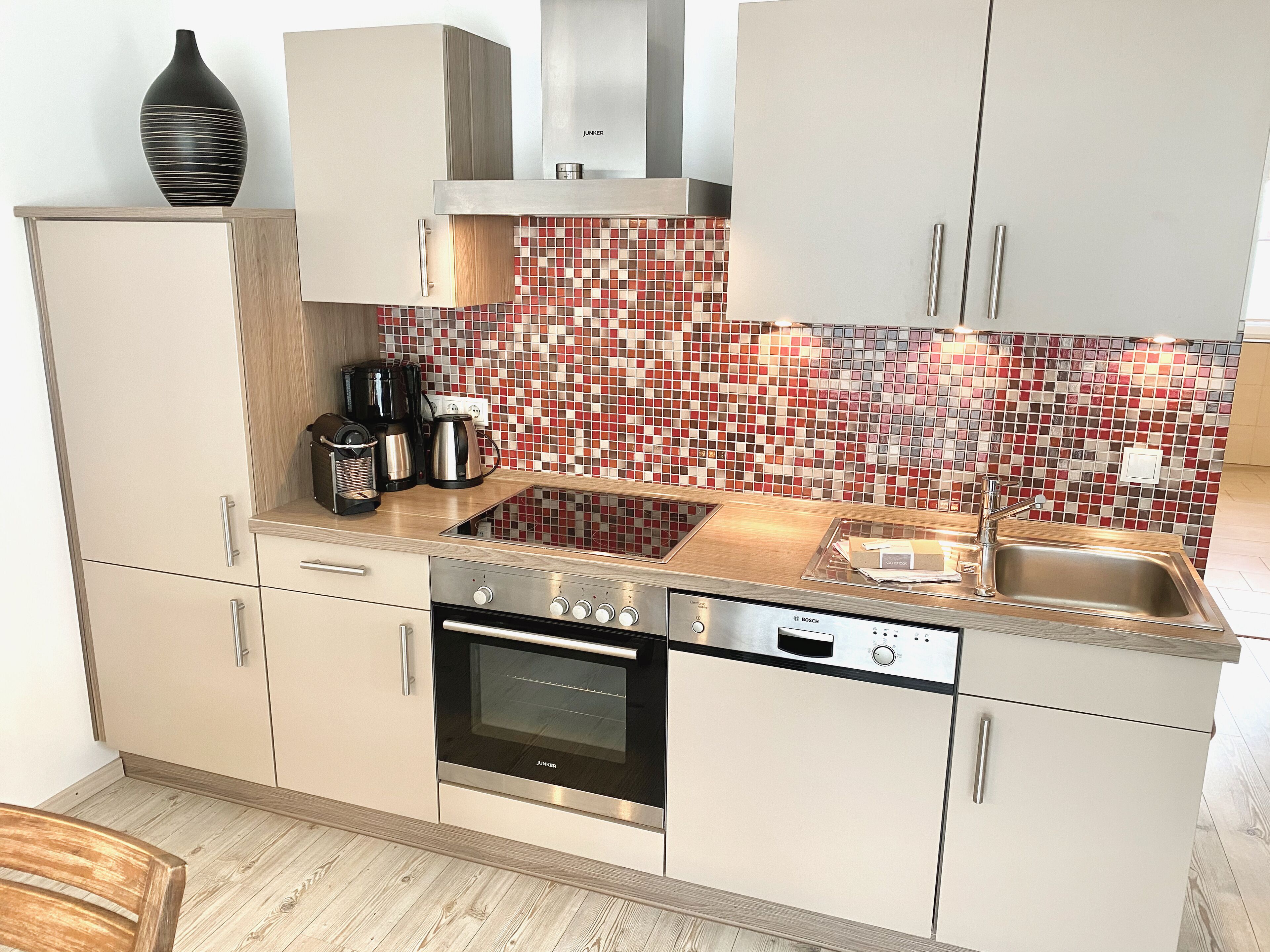 A modern kitchen with a Bosch dishwasher, a built-in oven, and a stainless steel sink.