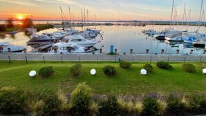 A marina with boats docked, a grassy area with spherical decorations, and a sunset in the background. - Moenchgut Living & Spa (Mönchgut-Granitz)