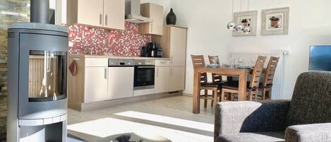 Una cocina moderna con estufa integrada, armarios de madera y un comedor con mesa y sillas.