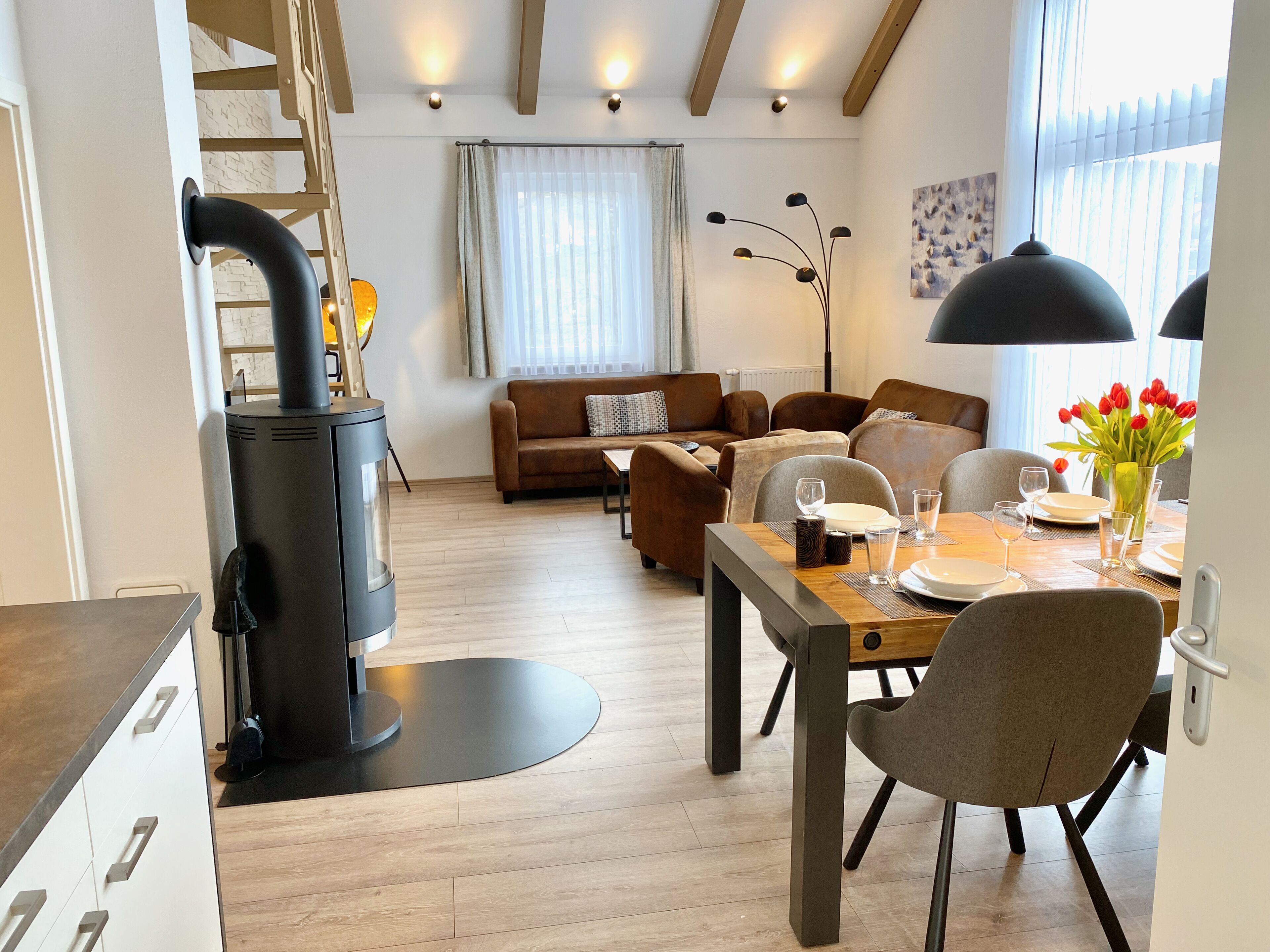 Un salon moderne avec un canapé, une table à manger et un poêle à bois noir.