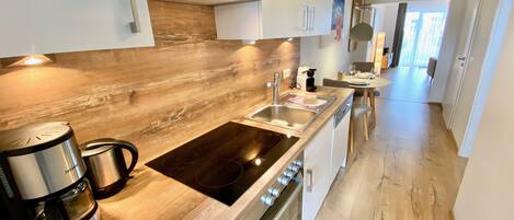 Eine moderne Küche mit Holzarbeitsplatten, Edelstahlgeräten und einem eingebauten Backofen.